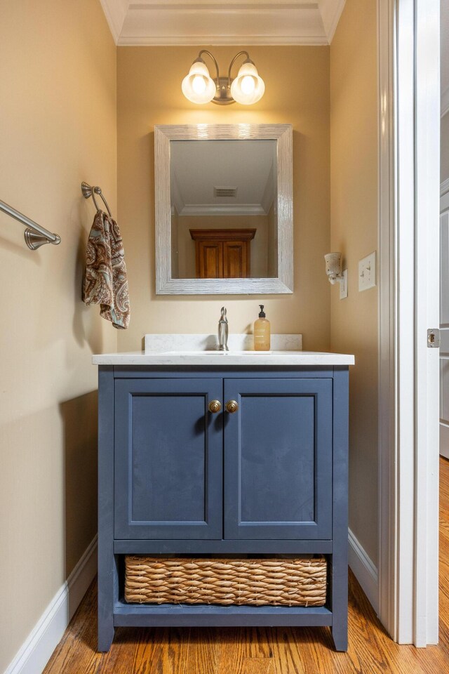 bathroom with wood-type flooring, crown molding, and vanity