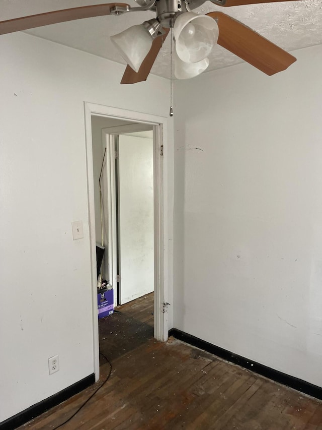 spare room with ceiling fan, dark wood finished floors, and baseboards