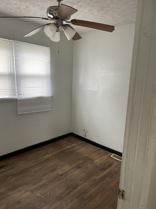 unfurnished room featuring visible vents, dark wood-type flooring, a ceiling fan, a textured ceiling, and baseboards