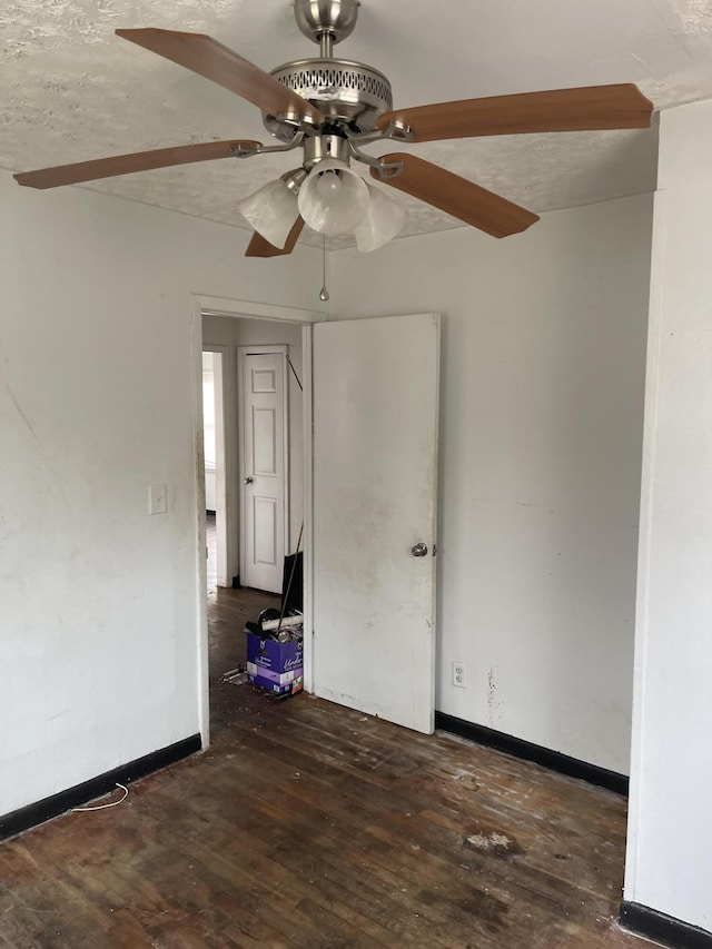 spare room featuring dark wood-style floors, ceiling fan, baseboards, and a textured ceiling