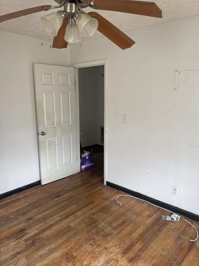 empty room featuring dark wood finished floors, baseboards, and ceiling fan