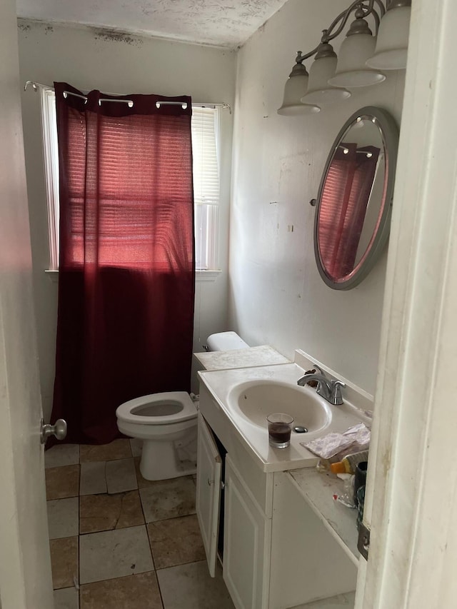 bathroom with toilet, a textured ceiling, and vanity