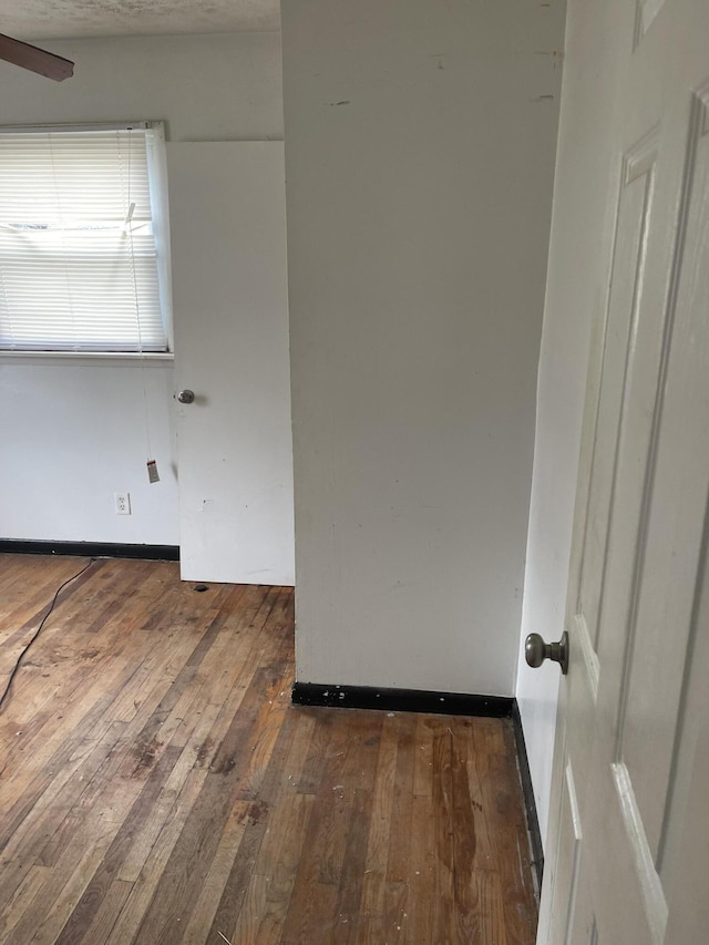 unfurnished room featuring dark wood finished floors, baseboards, and ceiling fan