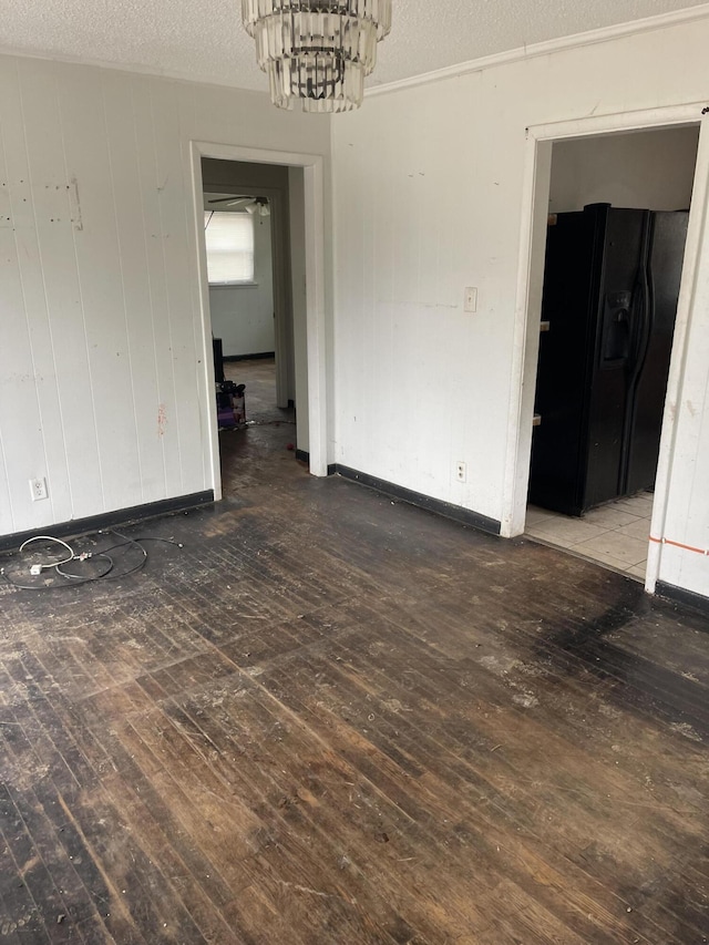 unfurnished dining area featuring baseboards, a textured ceiling, a chandelier, and dark wood-style flooring