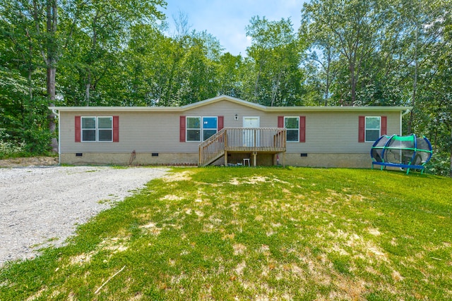 manufactured / mobile home featuring a wooden deck, a trampoline, and a front yard