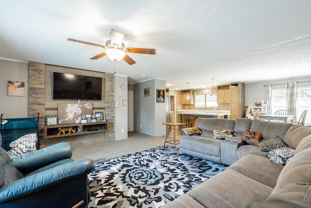 living room featuring light carpet, ornamental molding, a textured ceiling, sink, and ceiling fan