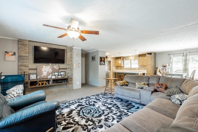 living room with a ceiling fan, light carpet, crown molding, and a textured ceiling
