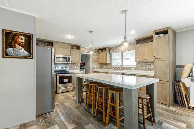 kitchen with a breakfast bar area, wood-type flooring, hanging light fixtures, a center island, and stainless steel appliances