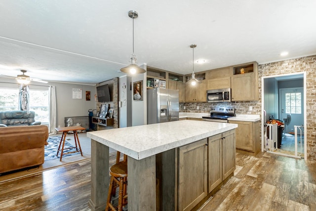 kitchen featuring open floor plan, light countertops, light wood-type flooring, stainless steel appliances, and backsplash