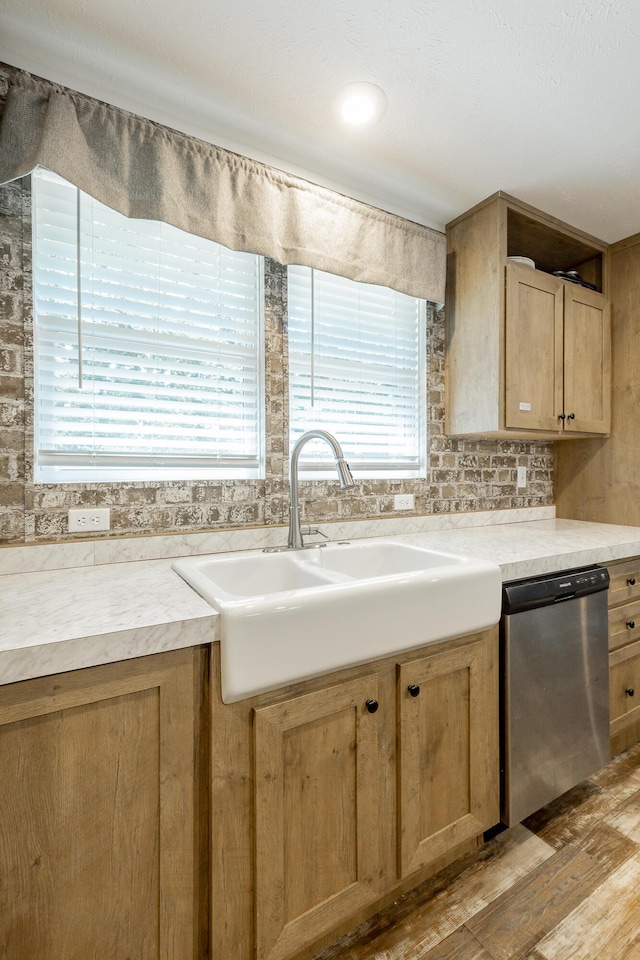 kitchen with dishwasher, light countertops, a sink, and decorative backsplash