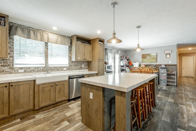 kitchen featuring stainless steel dishwasher, a kitchen breakfast bar, a sink, and dark wood-style flooring