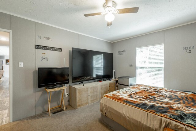 bedroom with light carpet, ornamental molding, ceiling fan, and a textured ceiling