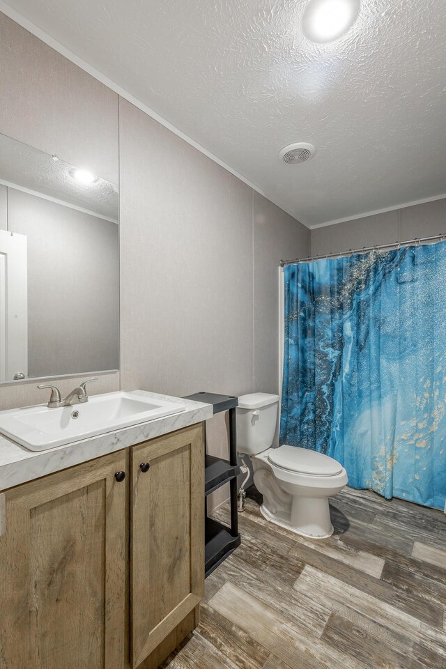 bathroom featuring toilet, vanity, hardwood / wood-style flooring, a textured ceiling, and a shower with curtain