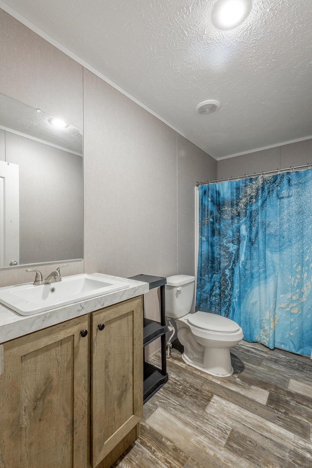 bathroom featuring vanity, toilet, a textured ceiling, visible vents, and wood finished floors