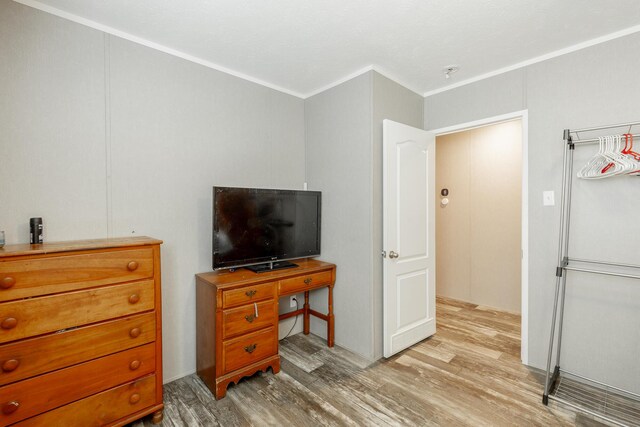 bedroom with light wood-type flooring and crown molding