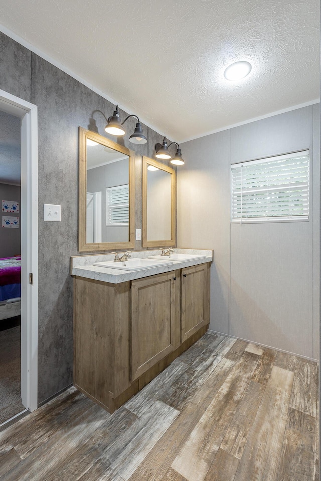 bathroom featuring connected bathroom, wood finished floors, double vanity, and a textured ceiling
