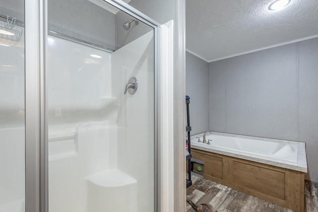 full bath with a bath, a textured ceiling, a shower stall, ornamental molding, and wood finished floors