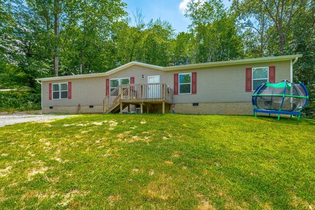 manufactured / mobile home with a trampoline, a front lawn, and a deck