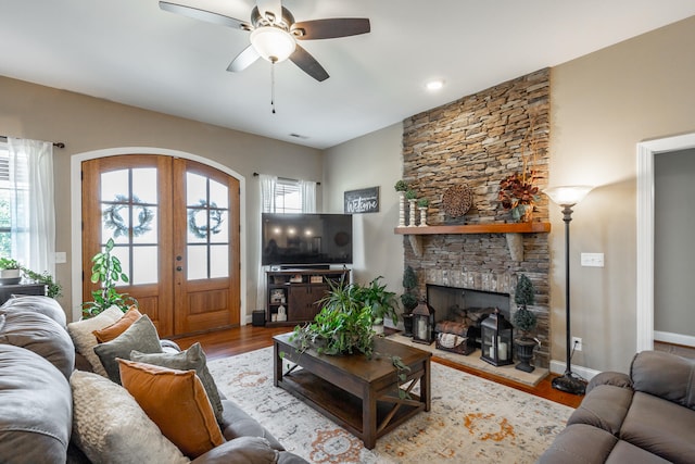 living room featuring light wood-type flooring, french doors, ceiling fan, and a healthy amount of sunlight