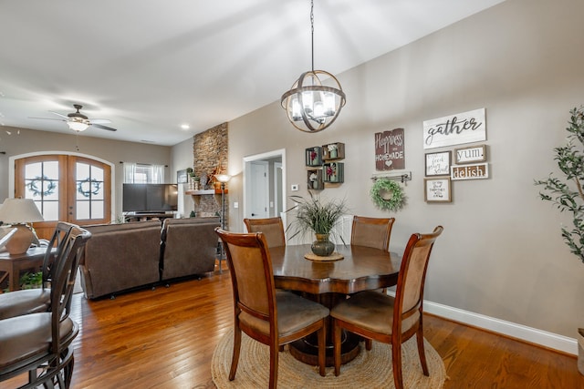 dining area with french doors, ceiling fan with notable chandelier, and hardwood / wood-style flooring