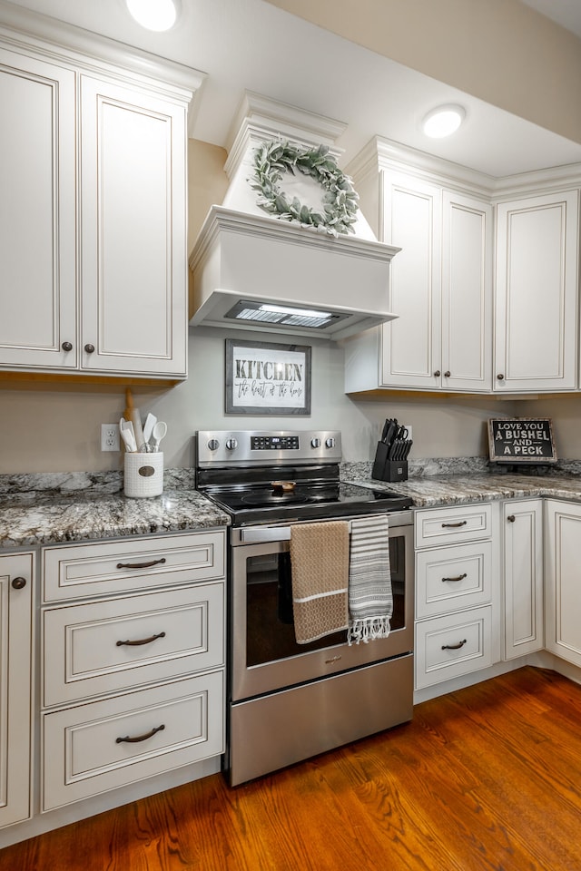 kitchen with white cabinets, electric range, hardwood / wood-style flooring, and light stone counters