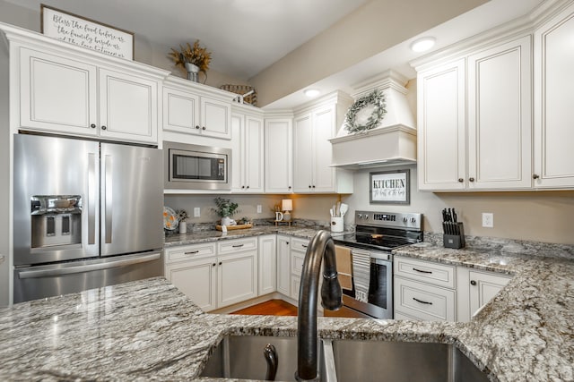 kitchen featuring white cabinetry, wood-type flooring, light stone counters, sink, and appliances with stainless steel finishes