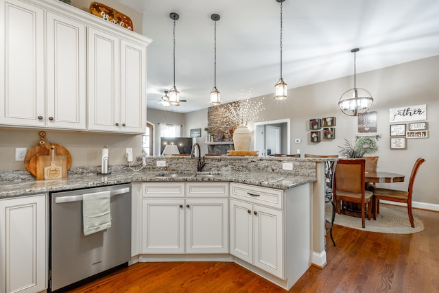 kitchen featuring stainless steel dishwasher, hanging light fixtures, sink, hardwood / wood-style flooring, and white cabinets