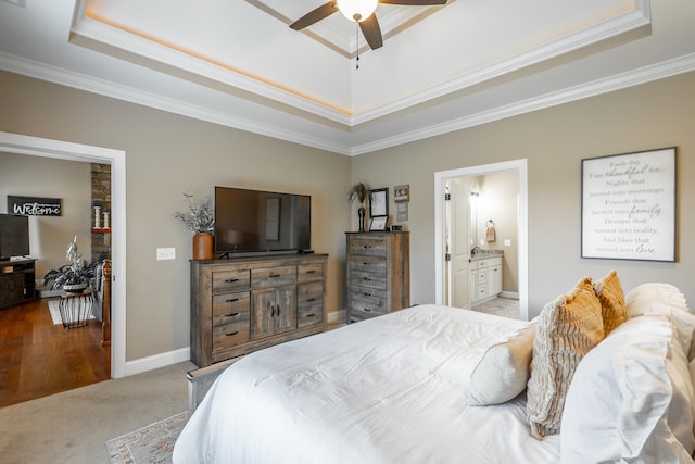 carpeted bedroom featuring ceiling fan, ornamental molding, a tray ceiling, and connected bathroom