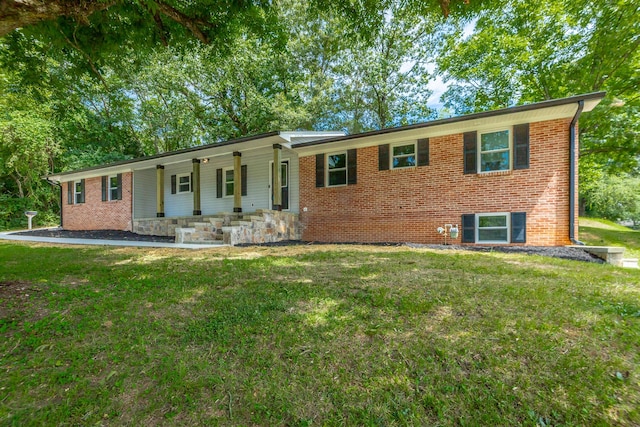 single story home featuring brick siding, a porch, and a front yard