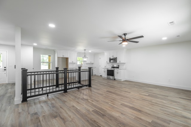 living room with light wood-type flooring, ceiling fan, and sink