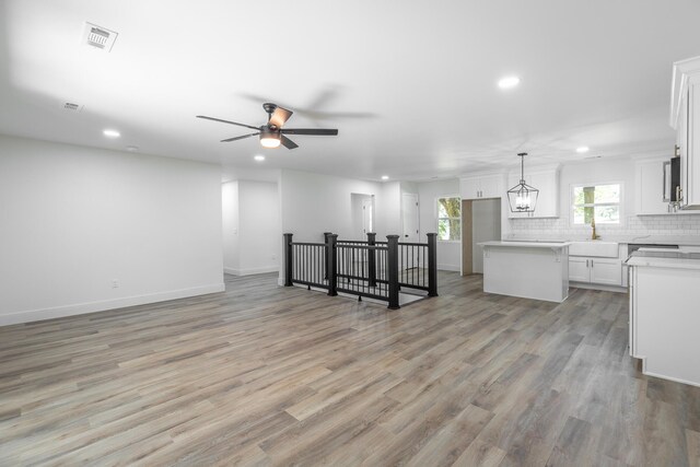 living room featuring ceiling fan with notable chandelier and light hardwood / wood-style flooring