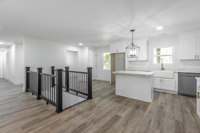 kitchen featuring dishwasher, white cabinetry, a kitchen island, and sink