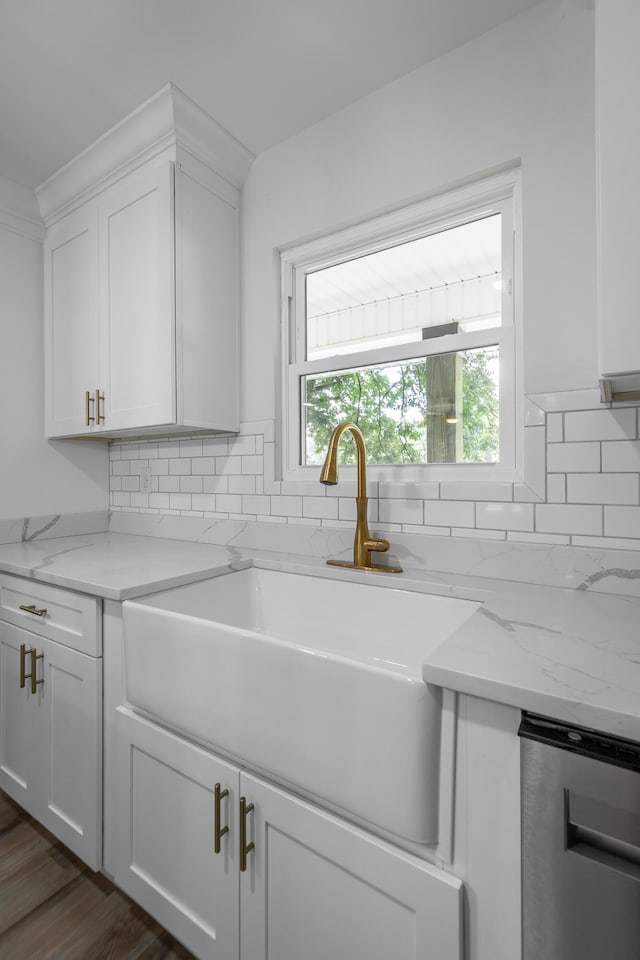 kitchen featuring sink, light stone countertops, and white cabinets