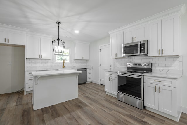 kitchen featuring wood-type flooring, light stone counters, appliances with stainless steel finishes, and white cabinetry