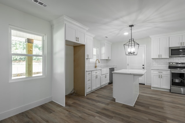 kitchen featuring appliances with stainless steel finishes, dark hardwood / wood-style flooring, a center island, and white cabinets