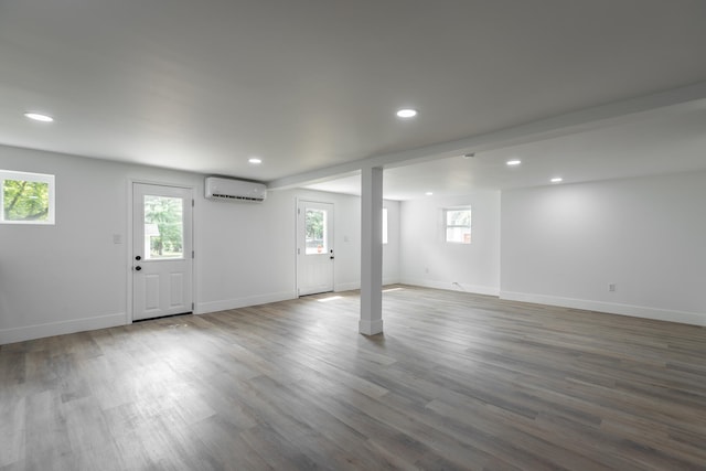 basement featuring hardwood / wood-style flooring, a wealth of natural light, and an AC wall unit