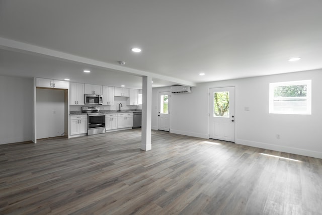 unfurnished living room with a wall mounted AC, hardwood / wood-style floors, and sink