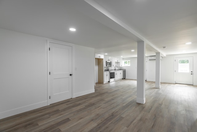 basement featuring hardwood / wood-style flooring, plenty of natural light, sink, and a wall mounted air conditioner