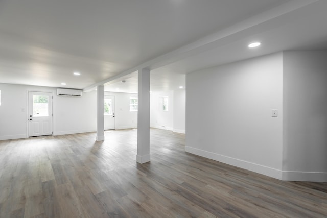 basement with a wall unit AC and hardwood / wood-style flooring