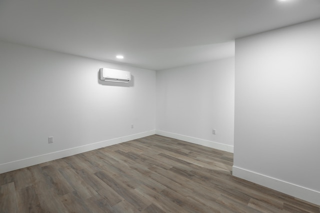 basement with hardwood / wood-style floors and an AC wall unit