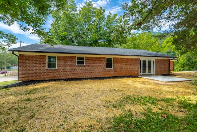 rear view of house featuring a lawn, a patio, and french doors