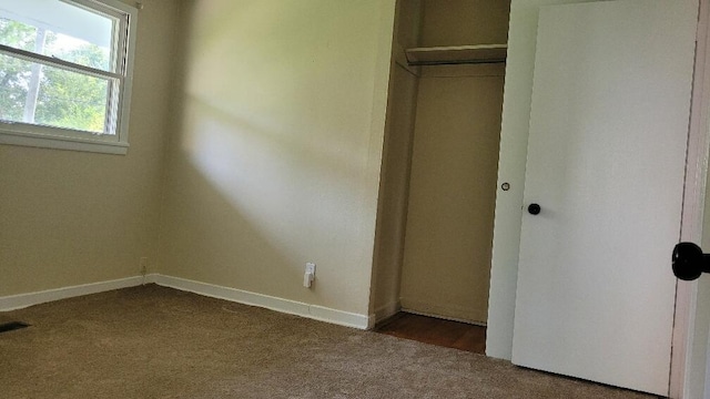 unfurnished bedroom with dark carpet and a closet