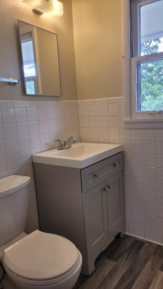 bathroom featuring vanity, toilet, hardwood / wood-style floors, and tile walls