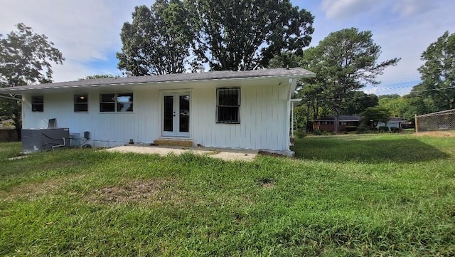 rear view of house featuring cooling unit and a yard