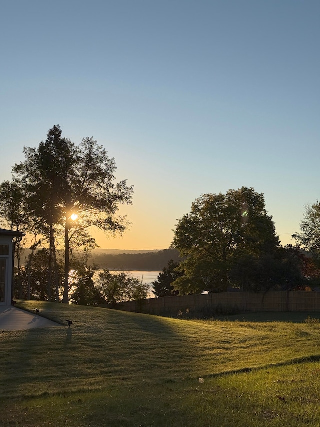 yard at dusk featuring a water view