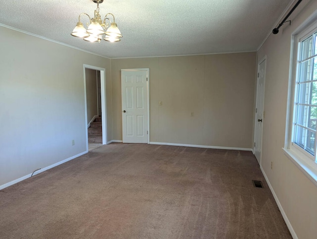 carpeted empty room with ornamental molding, a chandelier, and a textured ceiling