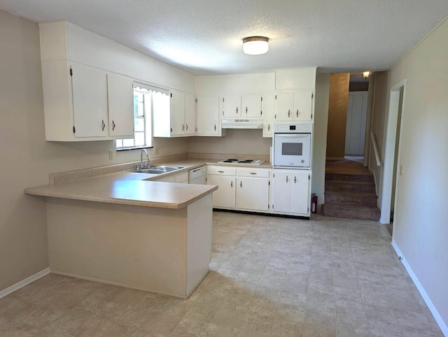 kitchen featuring white appliances, a textured ceiling, kitchen peninsula, sink, and white cabinets