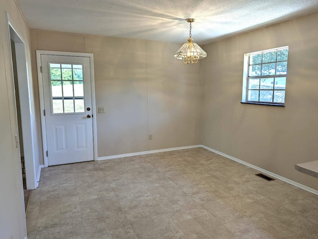 interior space featuring a textured ceiling and a chandelier