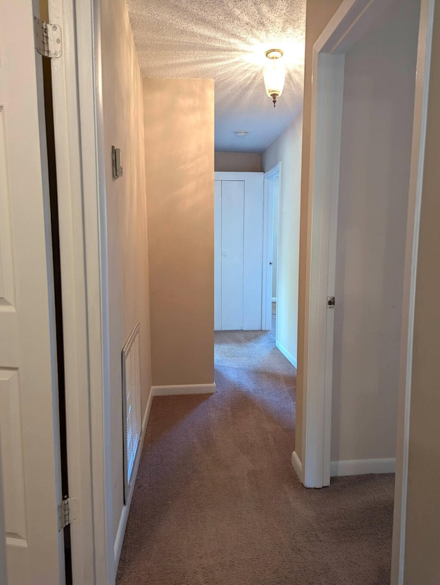 corridor with a textured ceiling and carpet floors