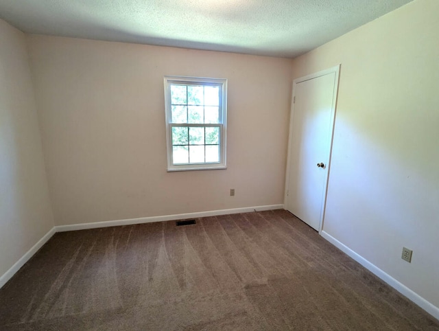 spare room featuring dark colored carpet and a textured ceiling